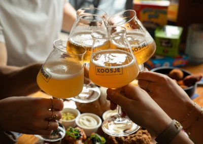 Vier mensen toosten met speciaalbier in Koosje-glazen
